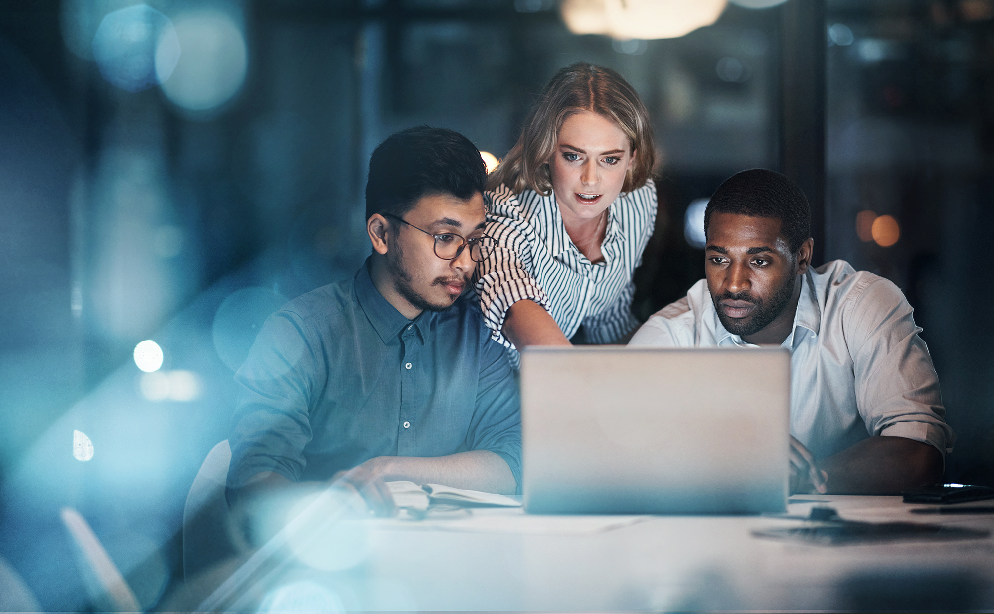 Three colleagues working on laptop in office late at night